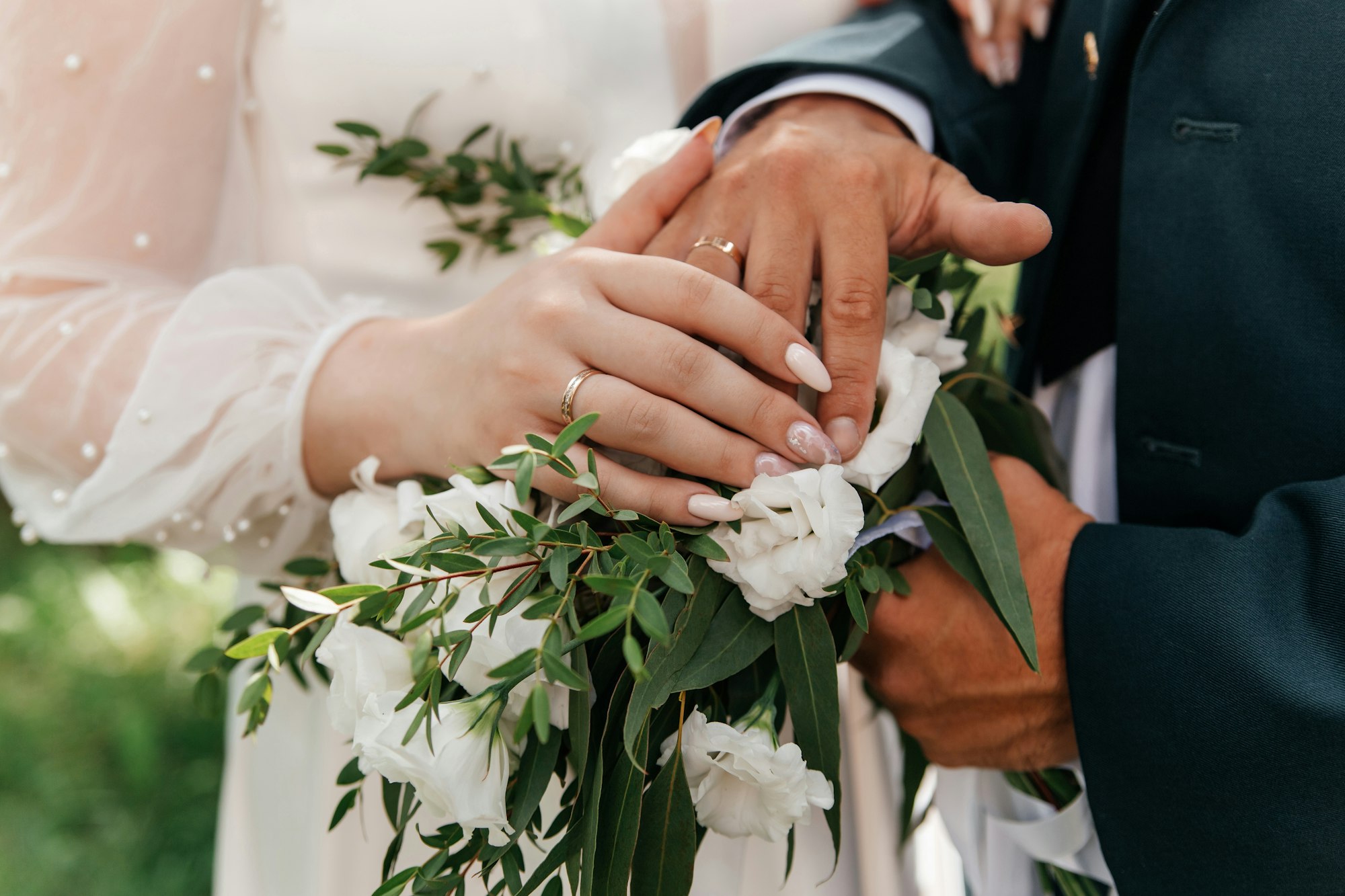 Hands of bride and groom with rings on wedding bouquet. Marriage concept