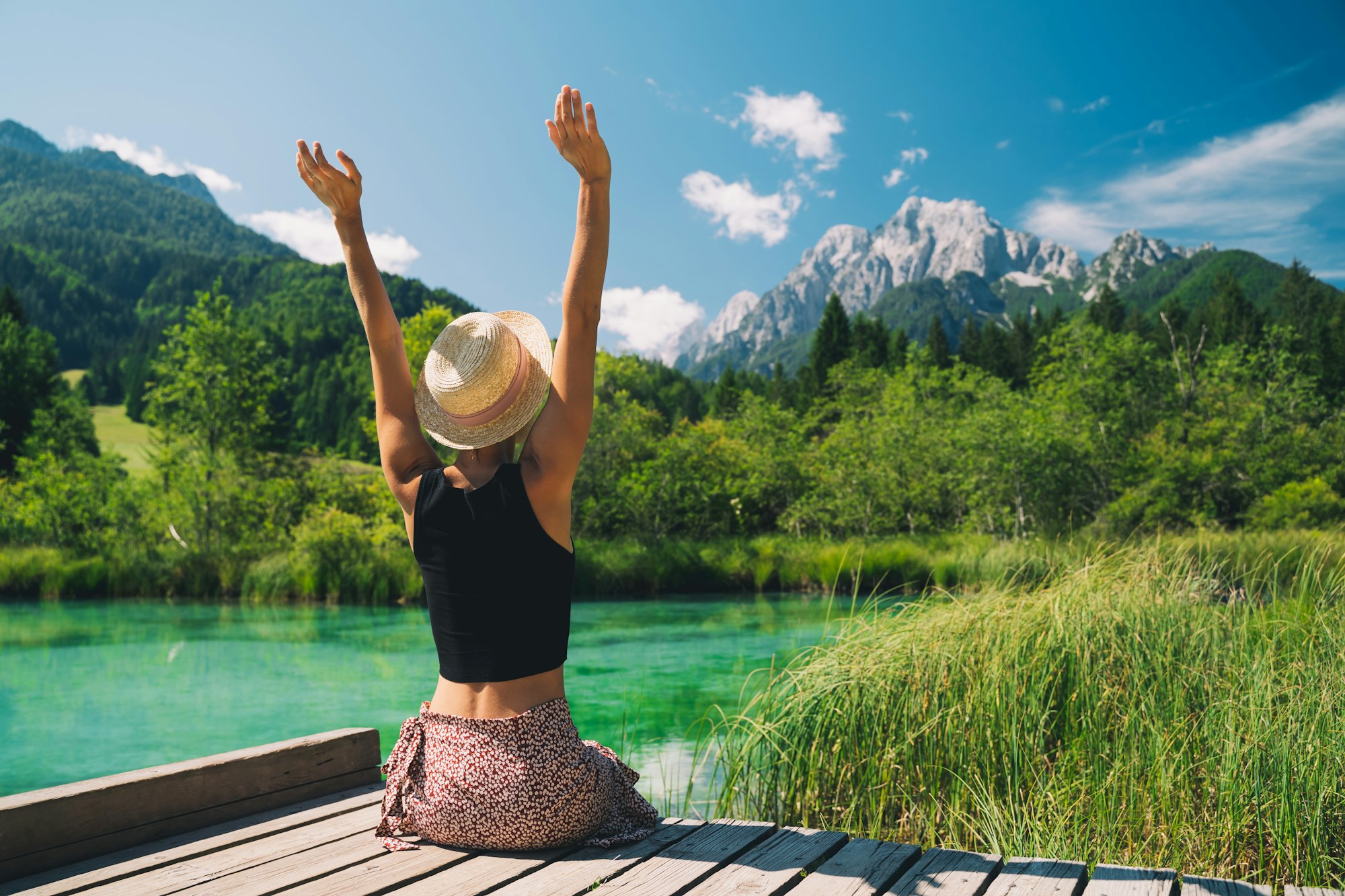 People in nature. Tourist woman with raised arms up in green nature background.